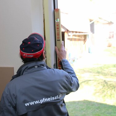 Mitarbeiter mit einer Wasserwaage bei der Fenstermontage