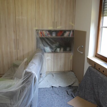 Kleiner Raum mit plastik überklebtem Schrank und Sofa